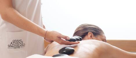 A person receiving a back massage with hot stones.