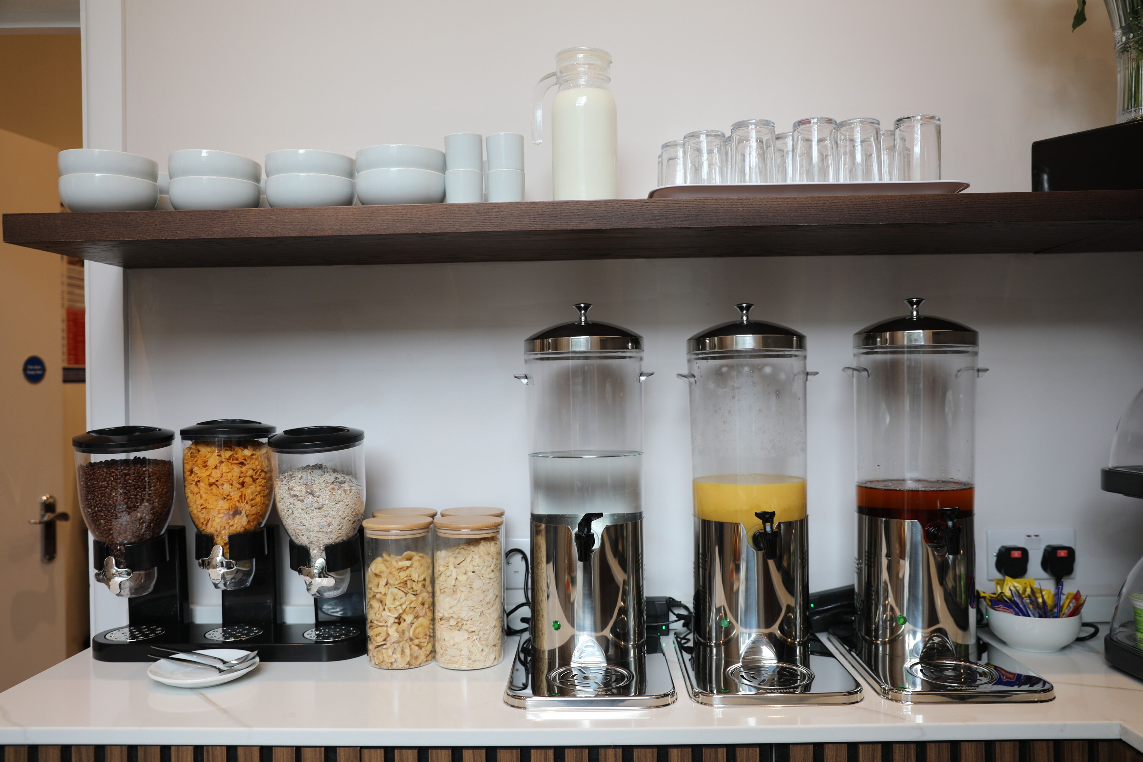A kitchen counter with various food dispensers, jars, and utensils.