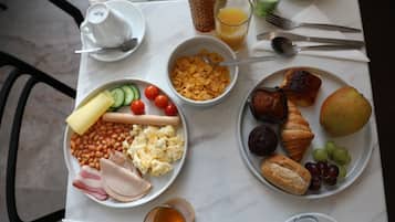 A breakfast table with plates of food, a glass of juice, and a cup of coffee.
