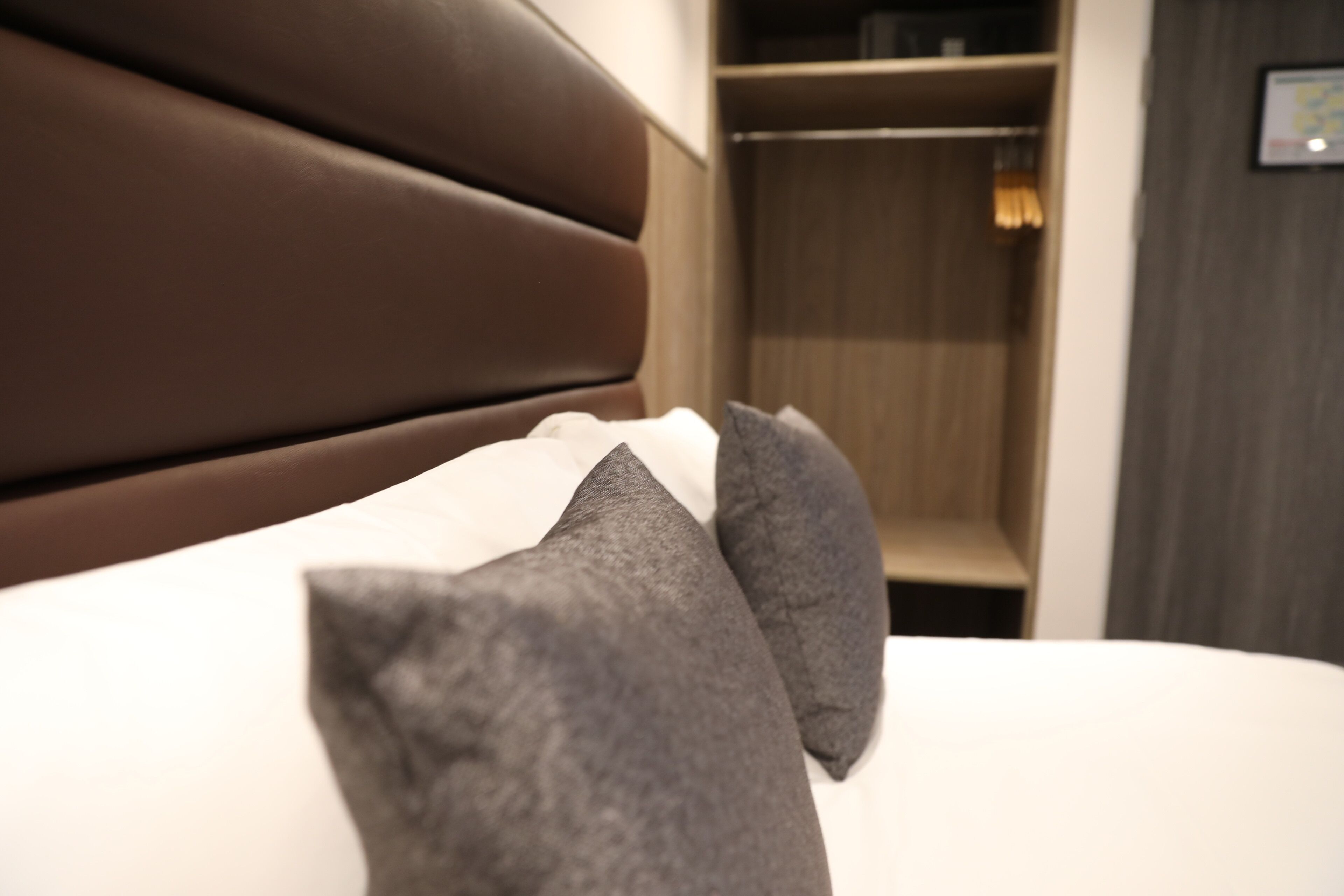 Ein Bett mit Kopfteil und Kissen, ein Holzschrank und ein gerahmtes Zertifikat an der Wand.