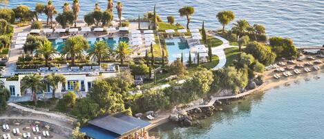 An aerial view of a resort with a central pool, multiple lounge areas, and a floating bar.