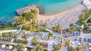 An aerial view of a resort with a beach, lounge areas, and a pool.
