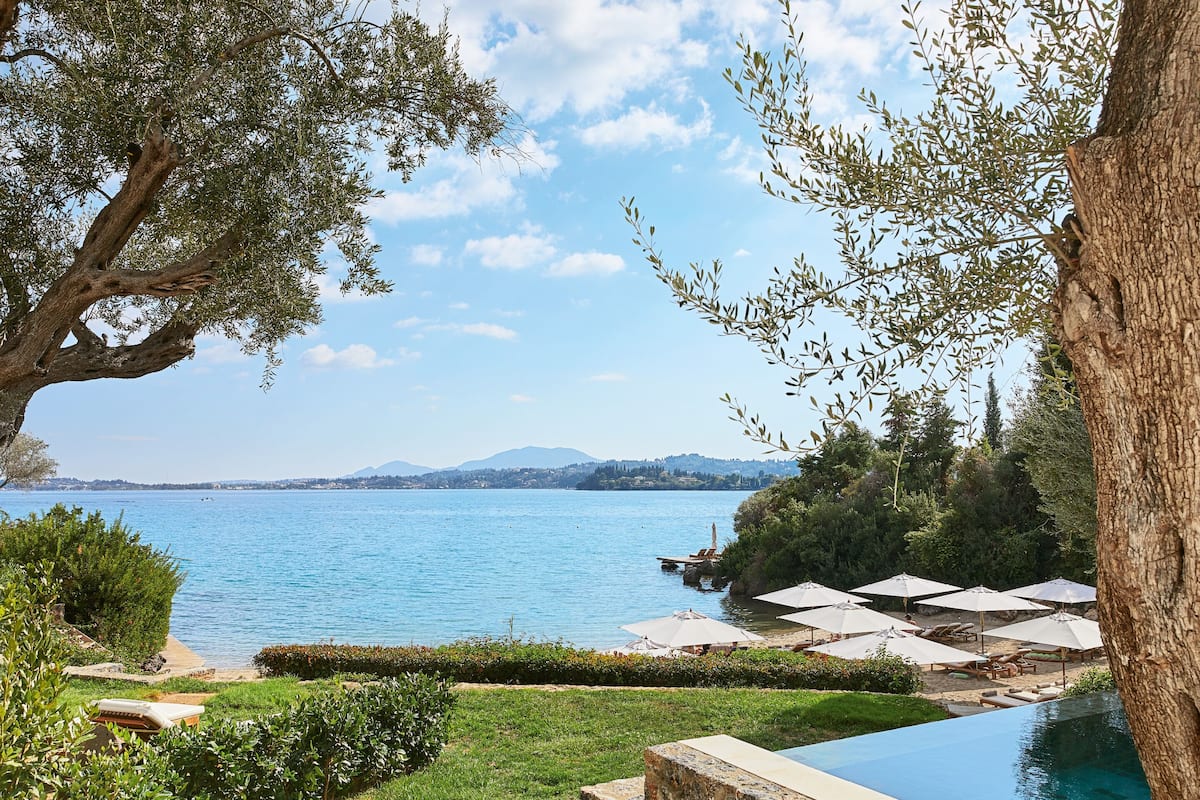 A poolside area with a view of the sea, lounge chairs, and umbrellas.