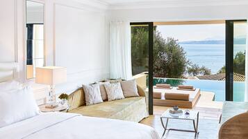Un dormitorio amplio con una cama grande, una zona de estar con sofá y vistas a una piscina y al océano.