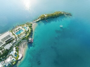 An aerial view of a coastal resort with a swimming pool, beach, and a boat dock. - Corfu Imperial, A Resort to Live (Corfu)