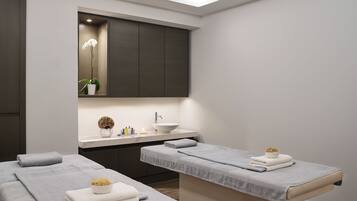 Two single beds with grey linens and bedside tables, a large mirror, and a wardrobe.