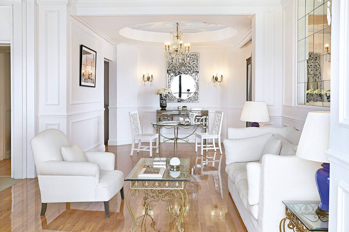 A luxurious living room with a central dining area, white furniture, and ornate decor.