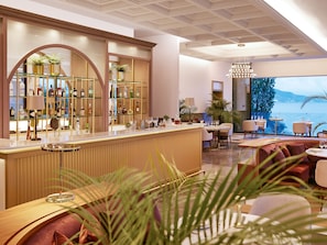 A bar area with a wooden counter, shelves with bottles, and a view of the sea.