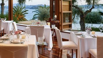 Un restaurant dont les tables sont dressées pour le service, avec vue sur un plan d’eau.