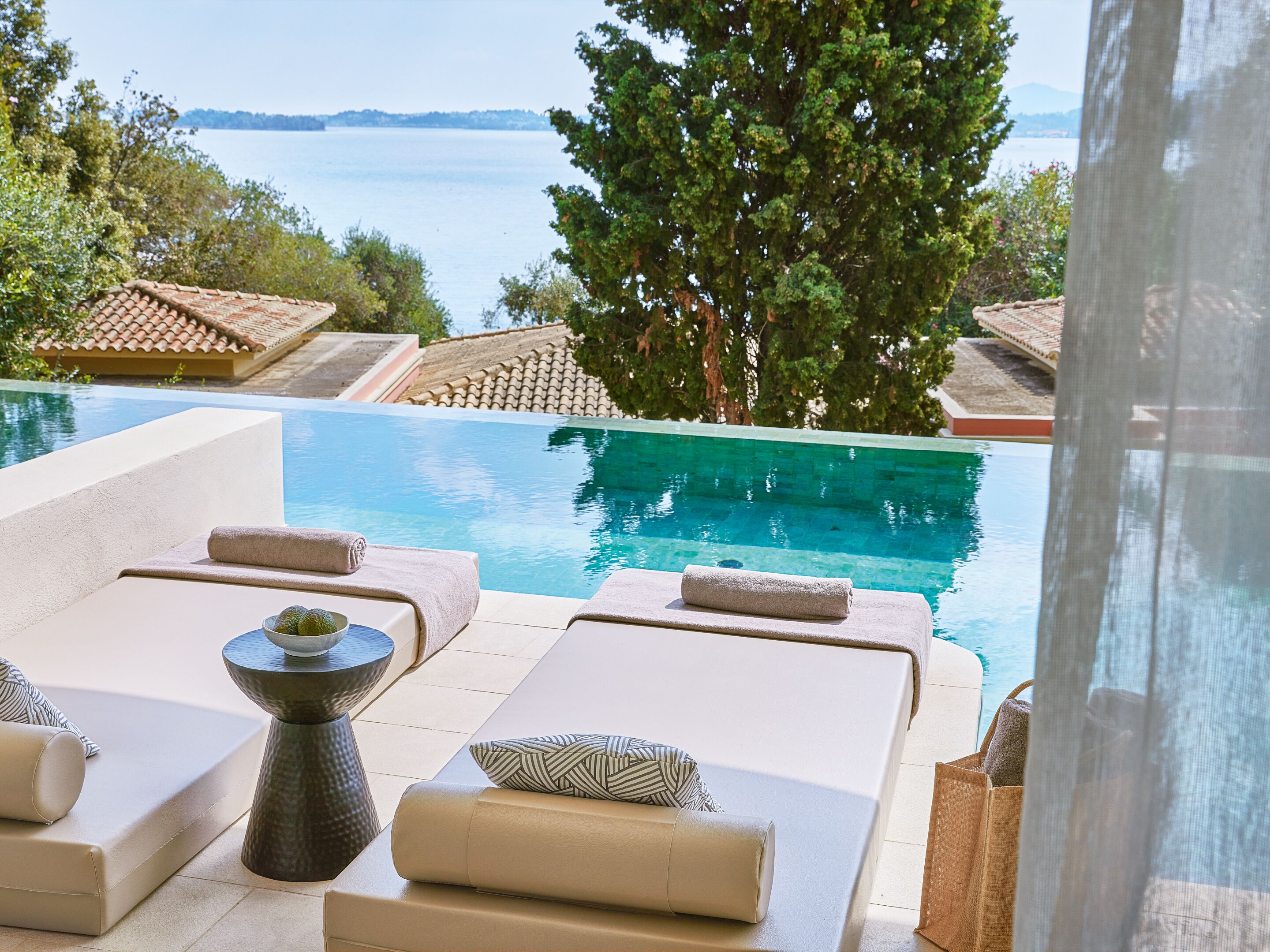 A poolside area with lounge chairs and a view of the sea.