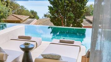 A poolside area with lounge chairs and a view of the sea.