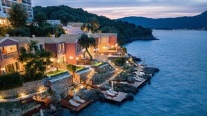 A coastal hotel with multiple buildings, a rocky shoreline, and a view of the sea.