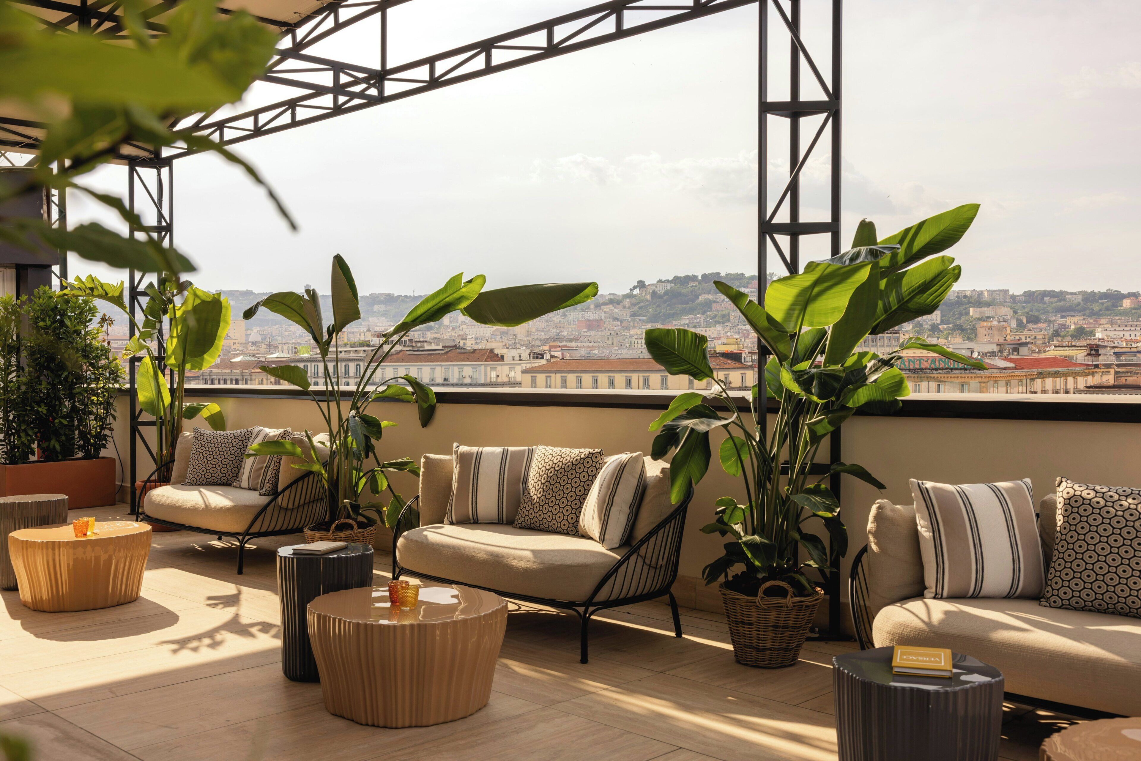 Una terrazza sul tetto con posti a sedere, piante in vaso e vista sulla città.