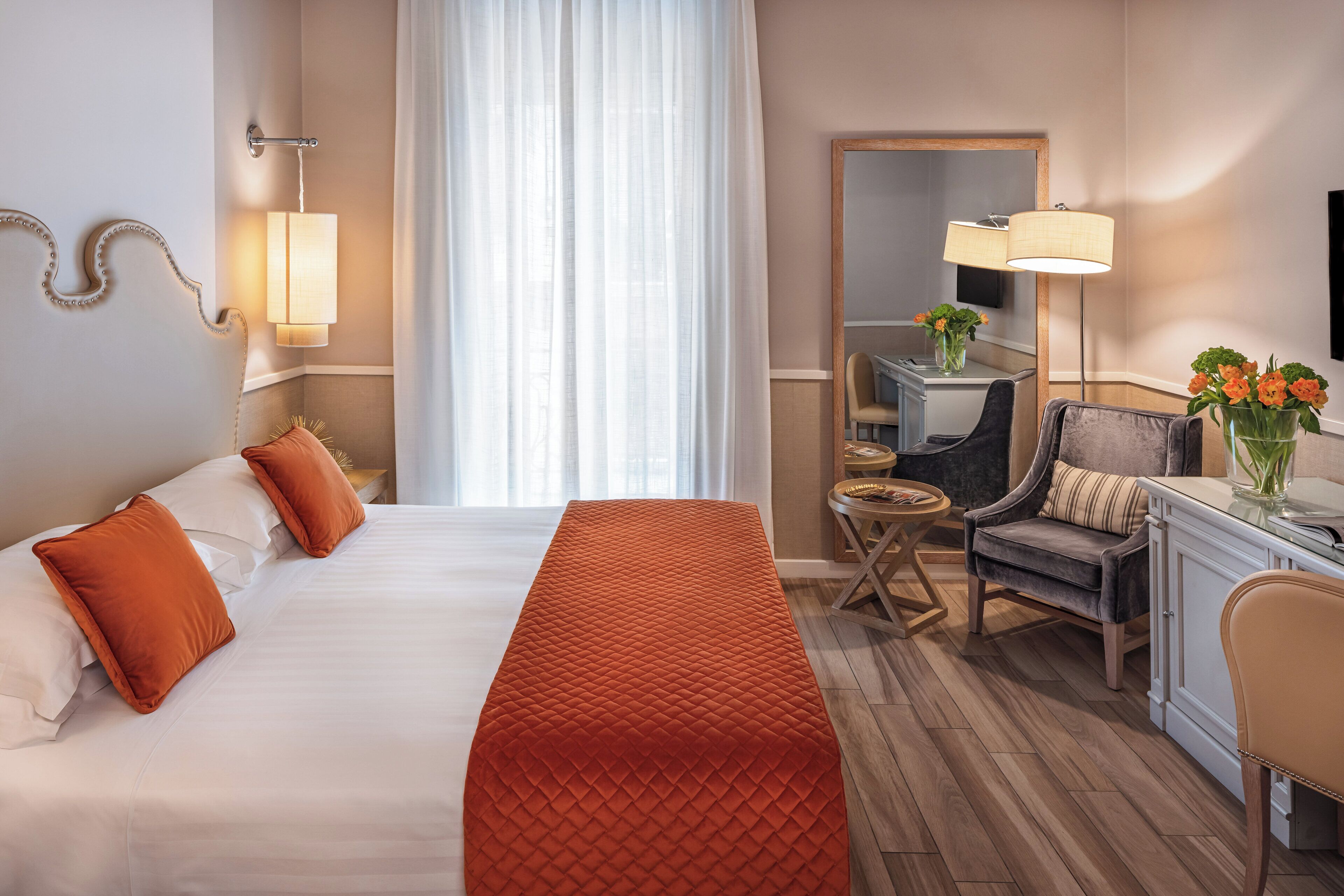 Una camera d'albergo con un letto, una scrivania, una sedia e uno specchio.