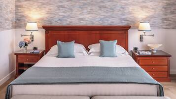 Een groot bed met een houten hoofdbord, twee nachtkastjes met lampen, en een bloemstuk op een van de tafels.