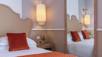 Een hotelkamer met een groot bed, een nachtkastje, een spiegel en een wandlamp.
