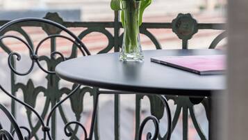 Un balcone con tavolo, una sedia e un vaso di fiori.