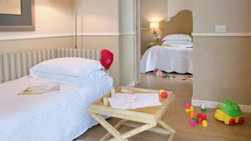 Ein Hotelzimmer mit zwei Betten, einem Holztisch und Spielzeug auf dem Boden.
