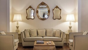 A living room with a beige sofa, two armchairs, a wooden coffee table, and three wall-mounted mirrors. - Starhotels Terminus (Naples)