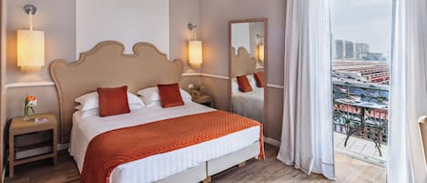 A hotel room with a large bed, two bedside tables, a nightstand, a mirror, and a view of a cityscape through a balcony.