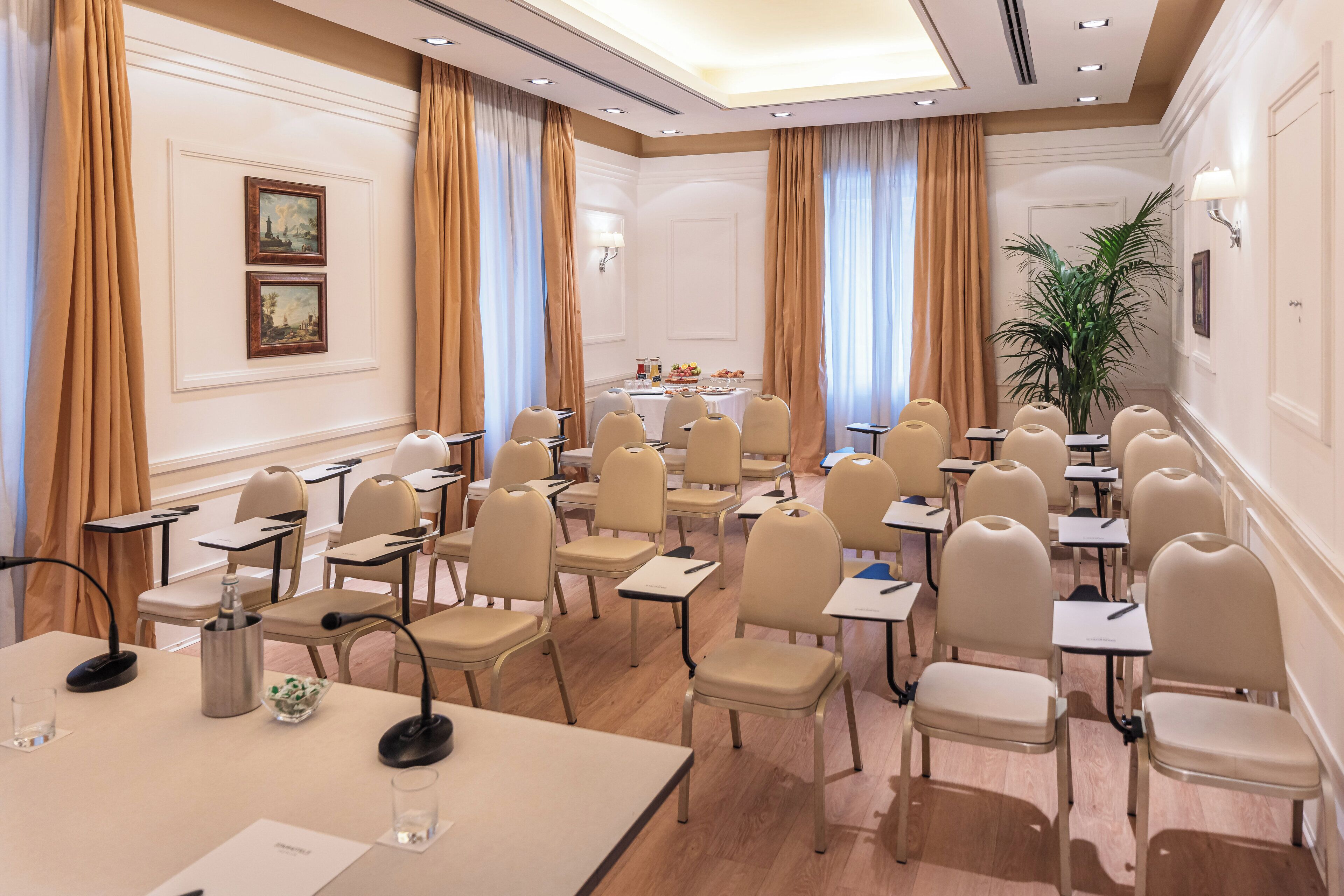 A conference room with rows of chairs, tables, and a podium.