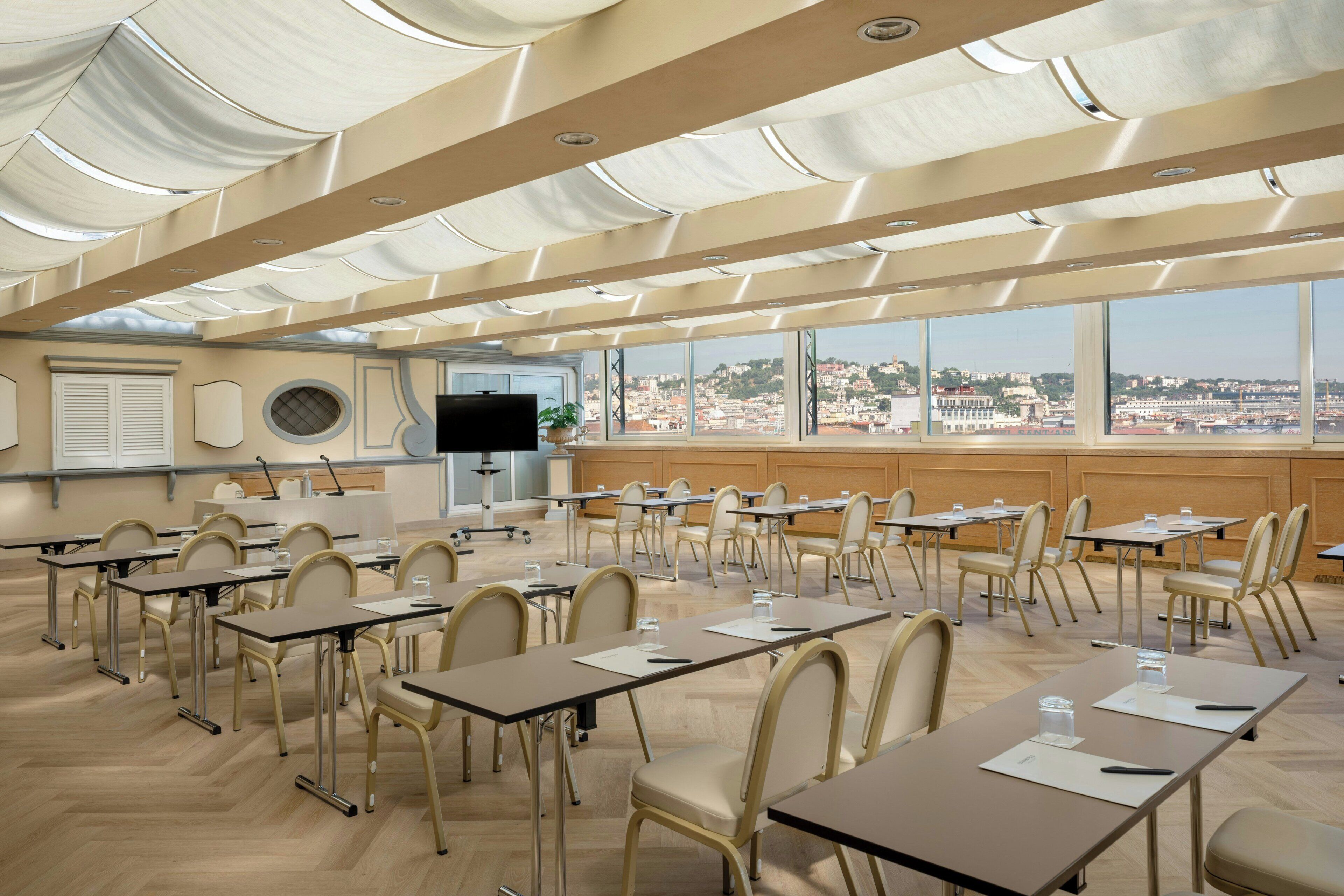 A conference room with a city view, large windows, and a modern ceiling design.