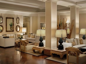 A spacious living room with a high ceiling, multiple seating areas, and decorative lamps. - Starhotels Terminus (Naples)