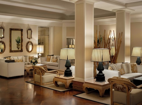 A spacious living room with a high ceiling, multiple seating areas, and decorative lamps.