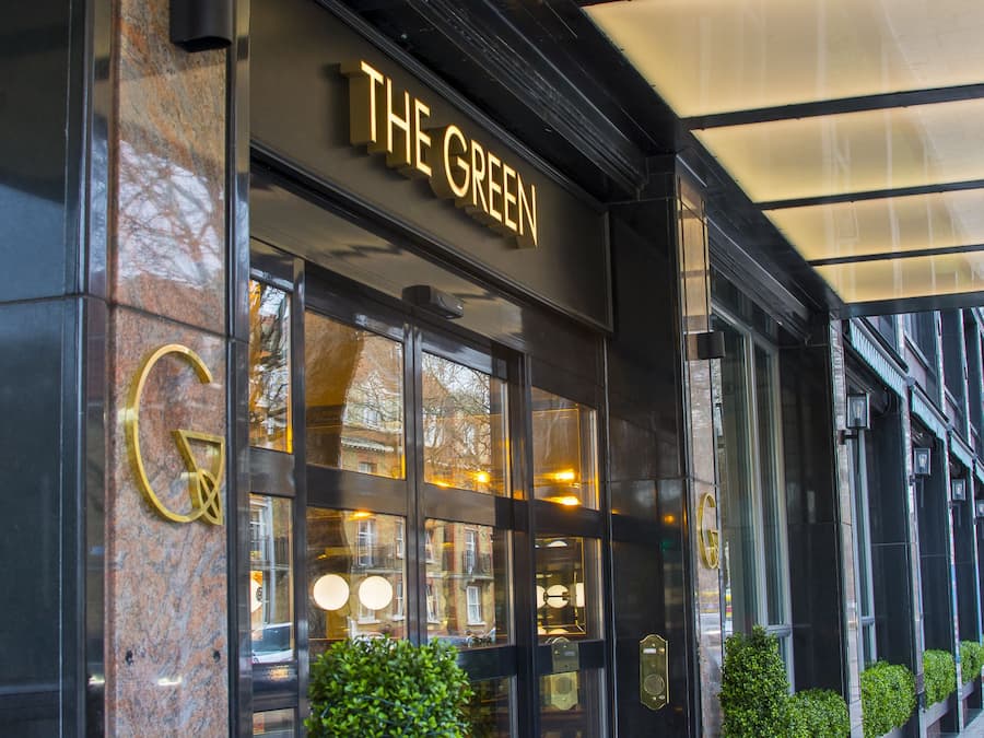 Fachada de un edificio con un letrero que dice THE GREEN y una serie de ventanas.