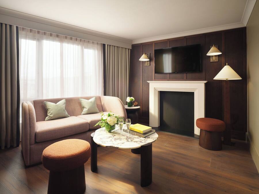 A living room with a sofa, ottoman, coffee table, fireplace, and a flat-screen TV.