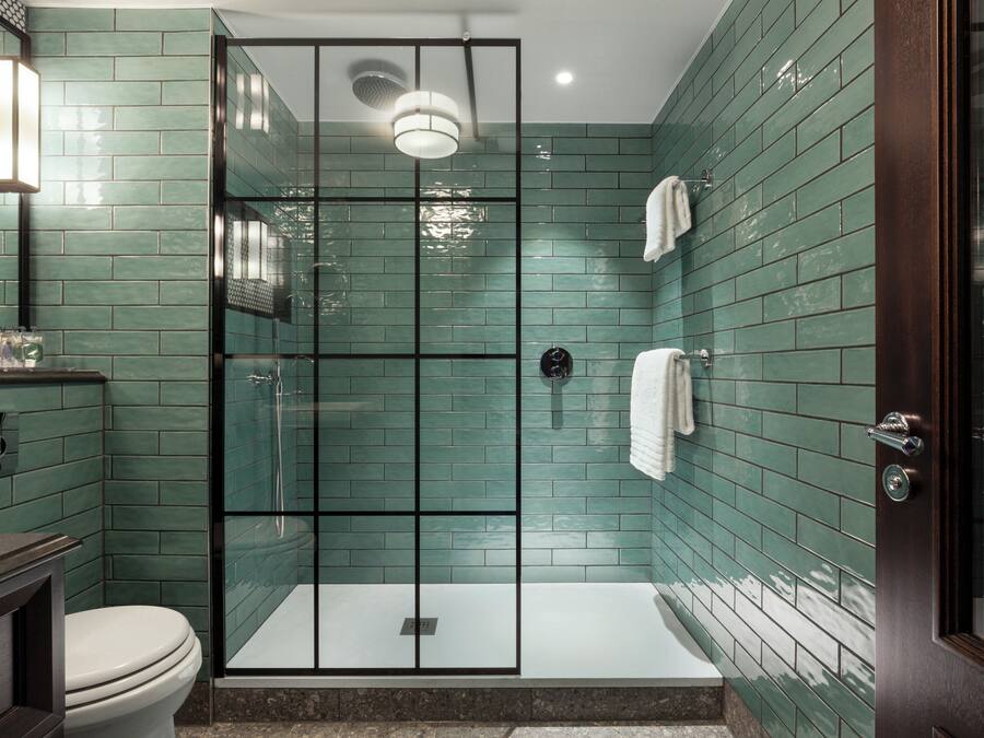 Un baño moderno con ducha de vidrio, inodoro blanco y tocador de madera oscura.