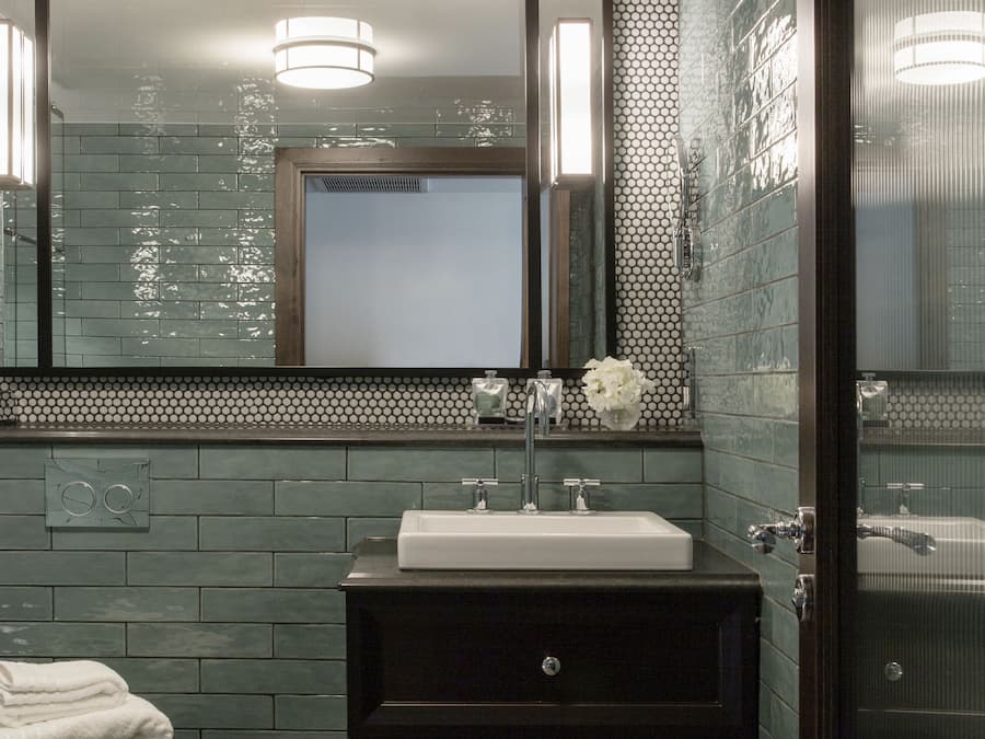 A modern bathroom with a large mirror, a sink, and a toilet.