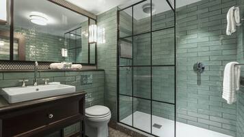 A bathroom with a sink, toilet, and glass-enclosed shower area.