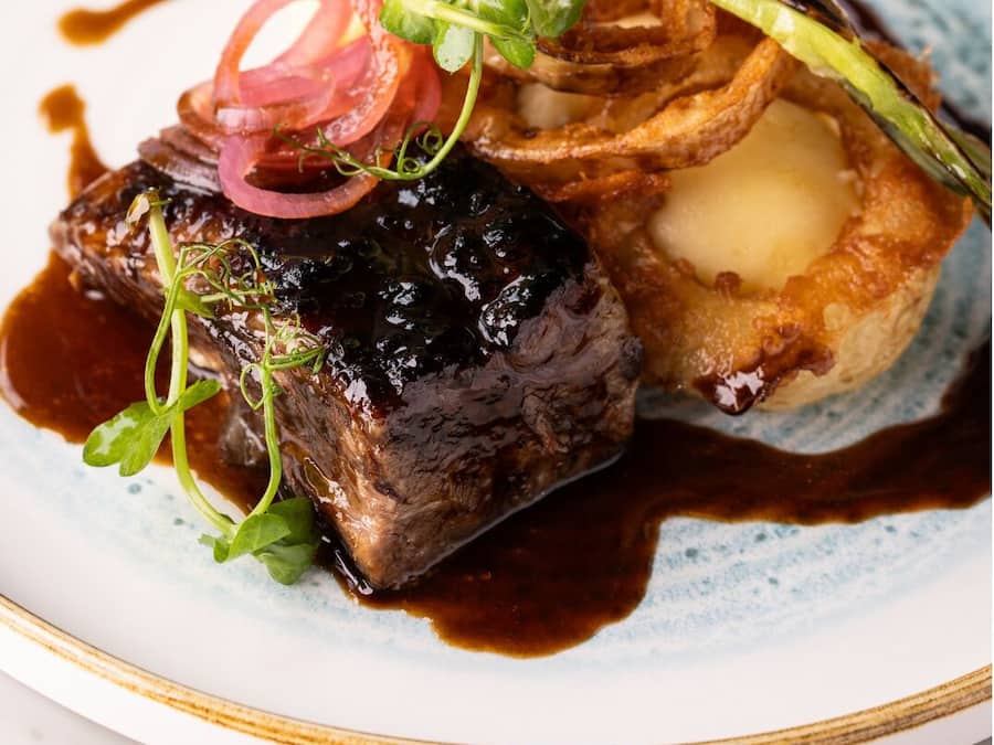 A plate with a steak, a baked potato, and some garnishes.