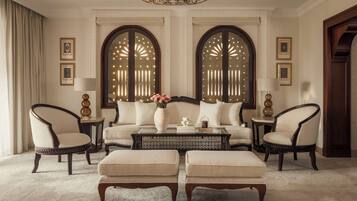 Uma sala de estar luxuosa com um sofá, duas poltronas, uma mesa de centro e um vaso decorativo.