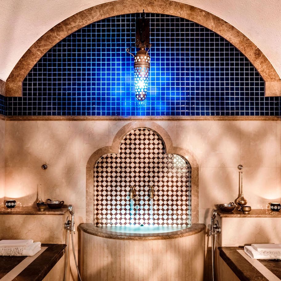 A spa room with a large bathtub, a blue-tiled wall, and a decorative arch above the tub.