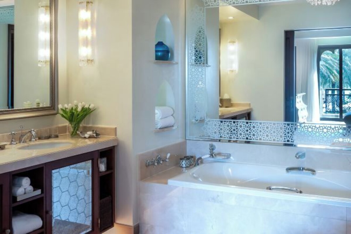 A modern bathroom with two sinks, a large bathtub, and a decorative mirror.
