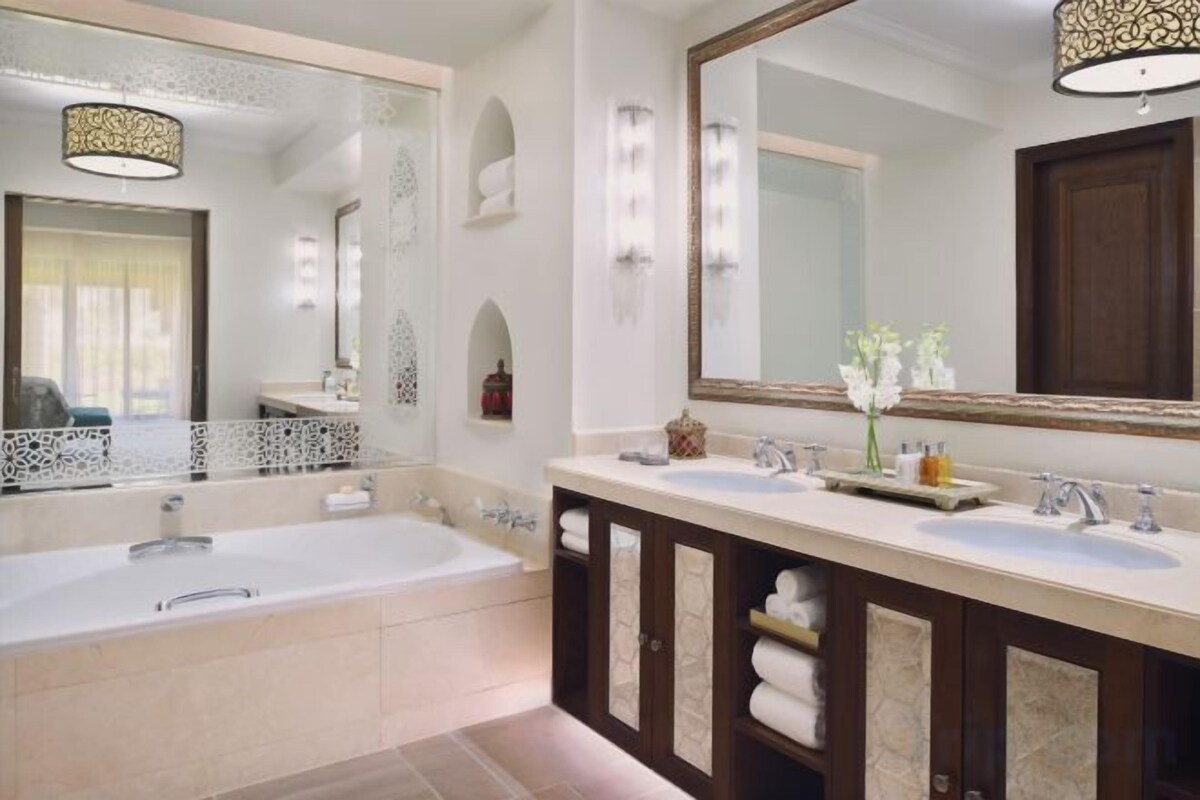 Un baño con una bañera grande, dos lavamanos y un espejo.