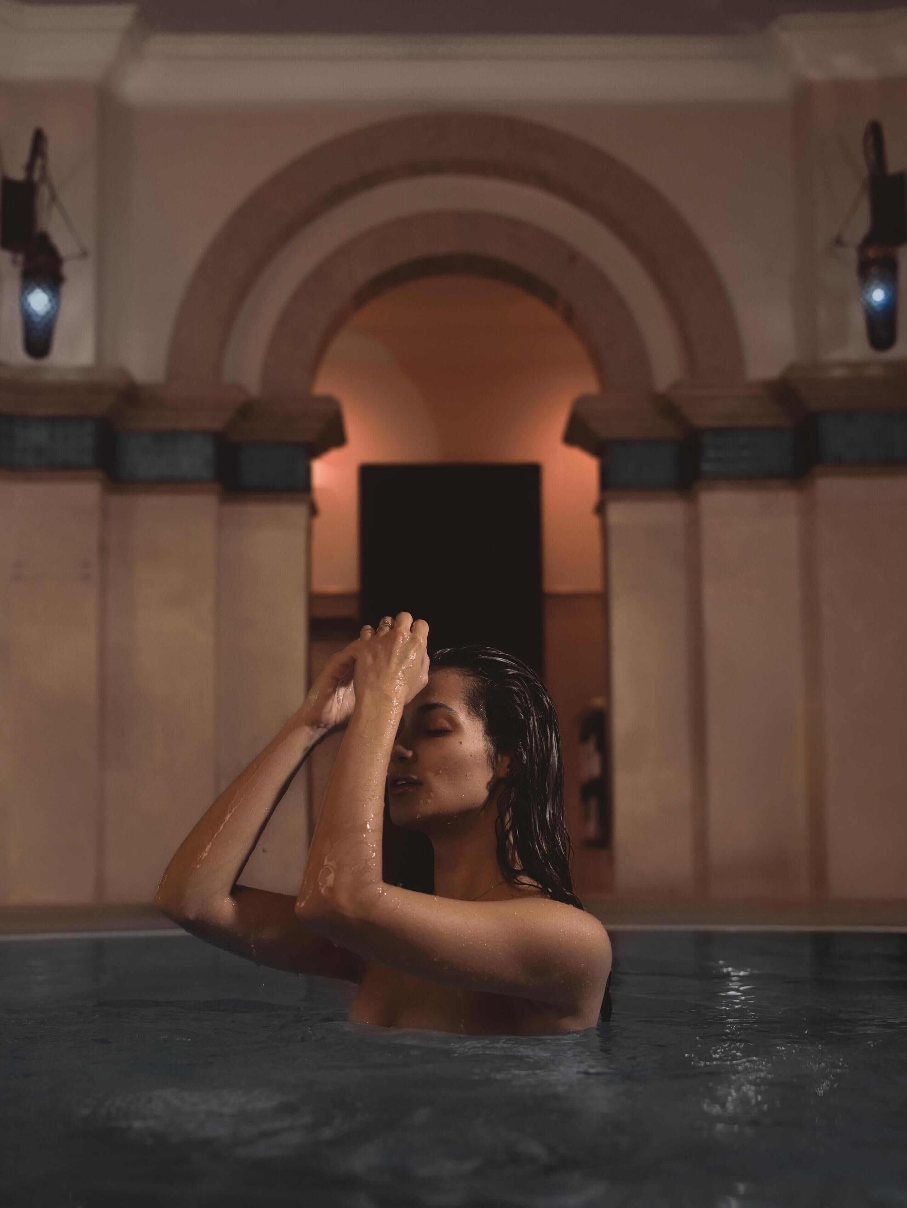 A person in a pool with arched ceilings and wall-mounted lights.
