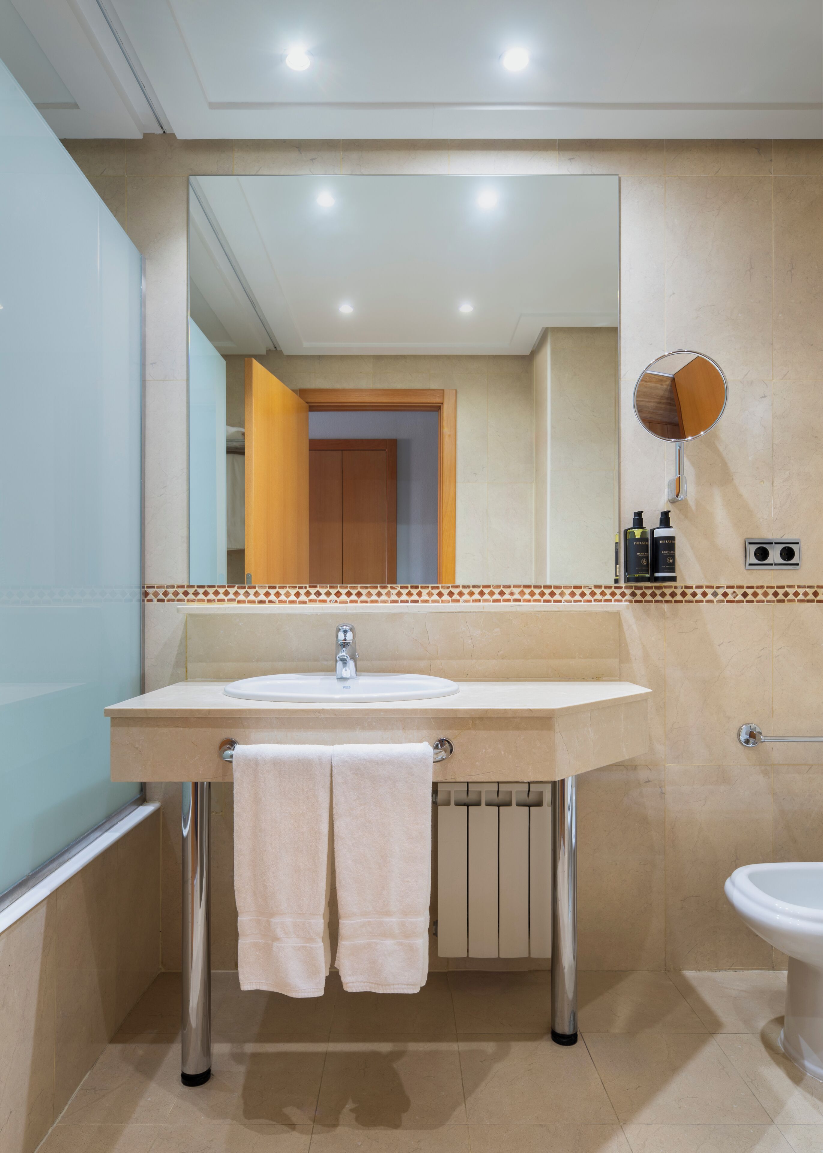 A bathroom with a sink, mirror, towel rack, and a toilet.