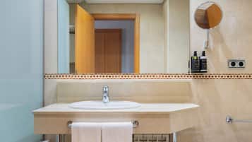 Un baño con lavamanos, espejo, toallero y retrete.