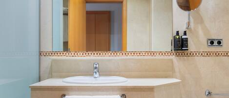 A bathroom with a sink, mirror, towel rack, and a toilet.
