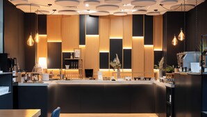 Una cocina moderna con una isla central, iluminación colgante y una pared decorativa de madera.