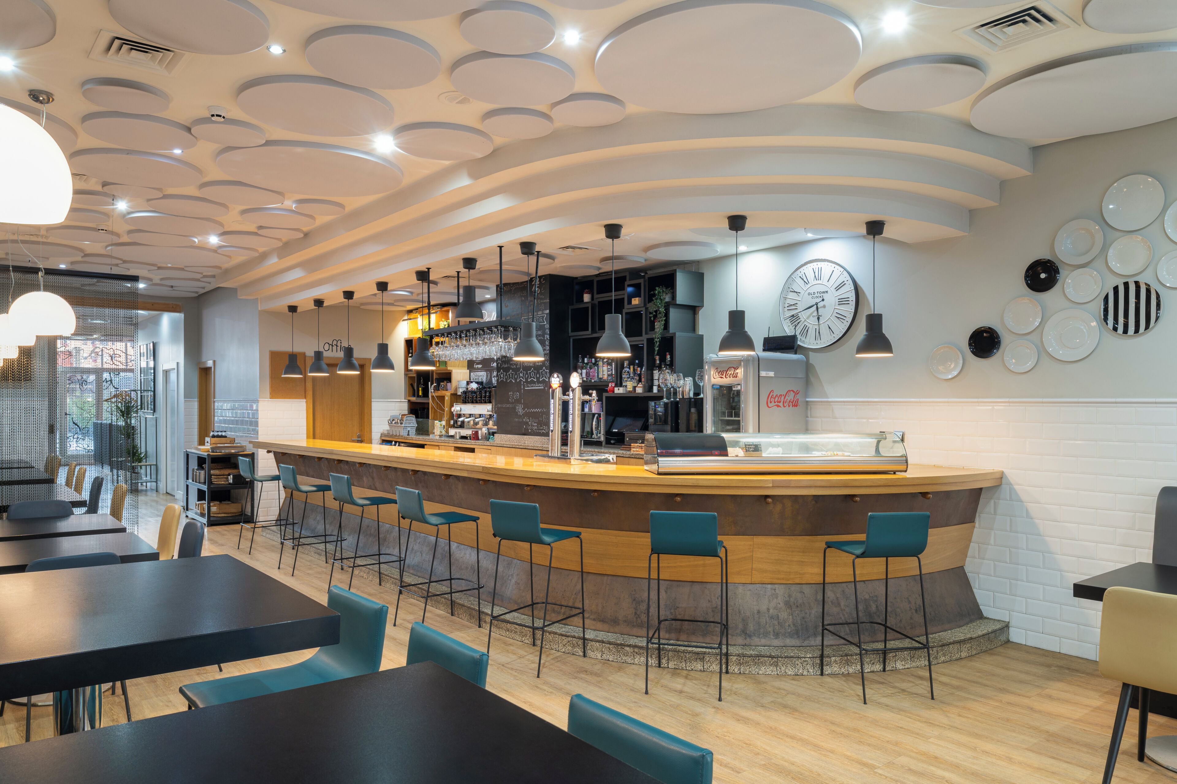 Un espace bar moderne avec un comptoir, des tabourets de bar et une horloge au mur.