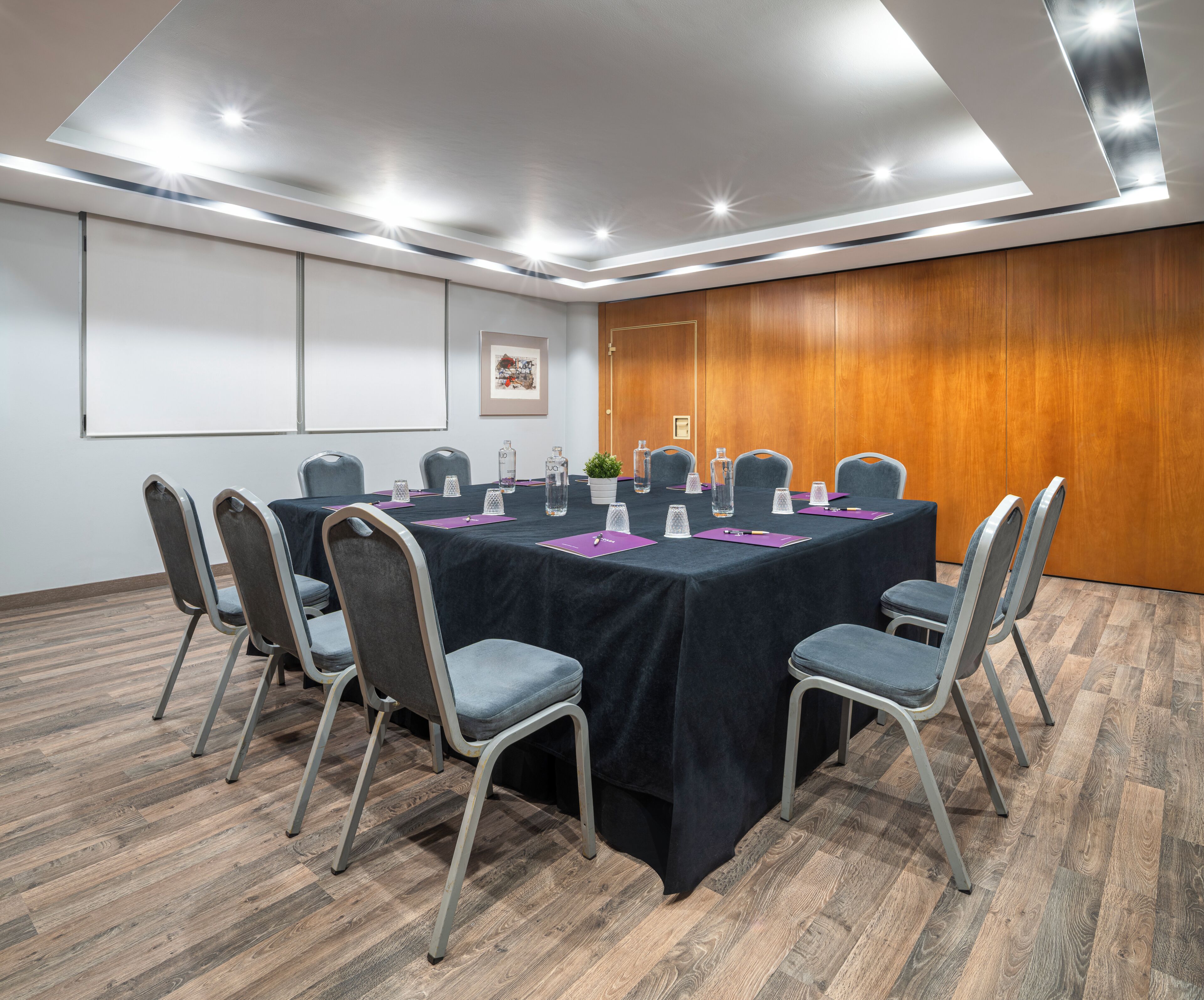 A conference room with a long table, chairs, and a projector screen.