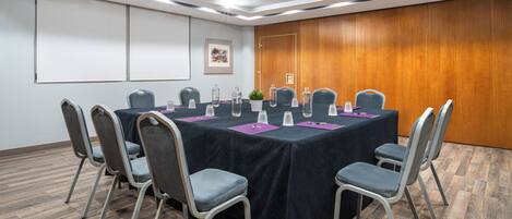 A conference room with a long table, chairs, and a projector screen.
