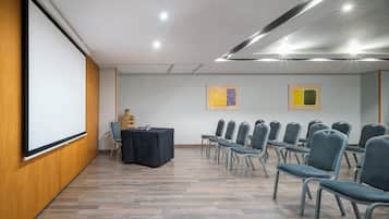 A conference room with a projector screen, a table with chairs, and two framed artworks on the wall.
