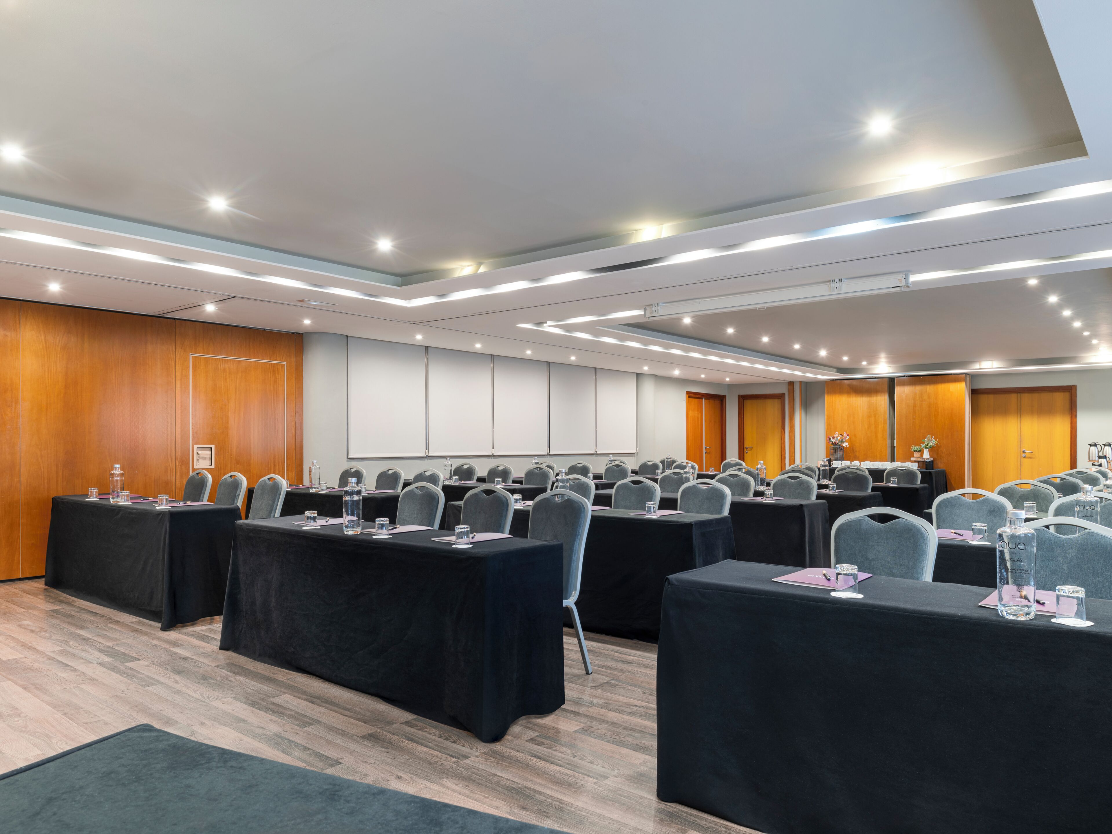 A conference room with multiple tables, chairs, and a projector screen.