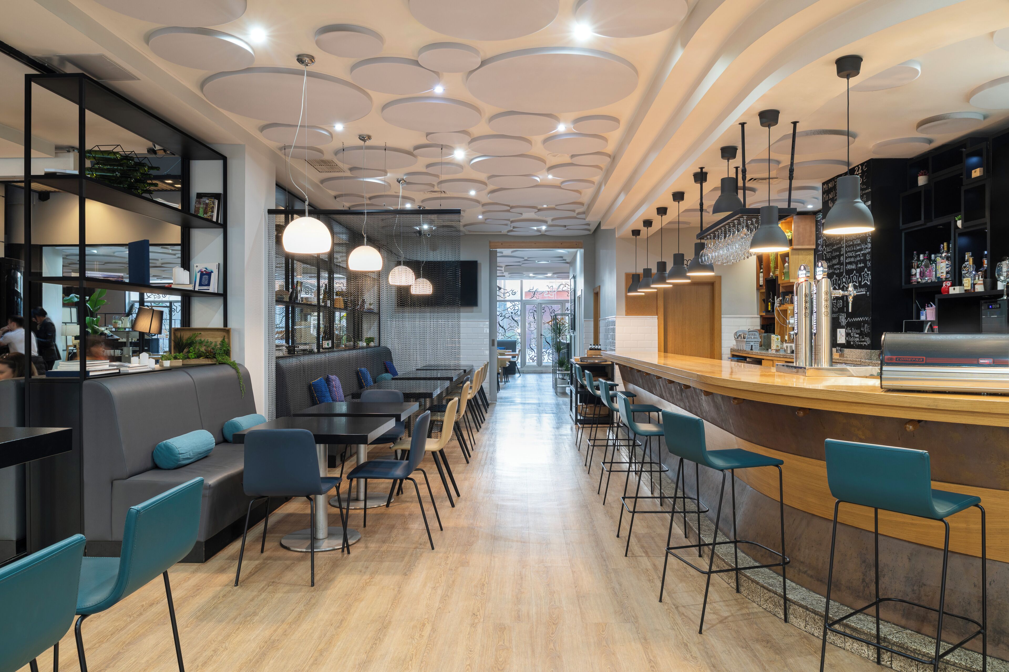 Un espacio moderno de bar con asientos, una barra y vistas al salón comedor.