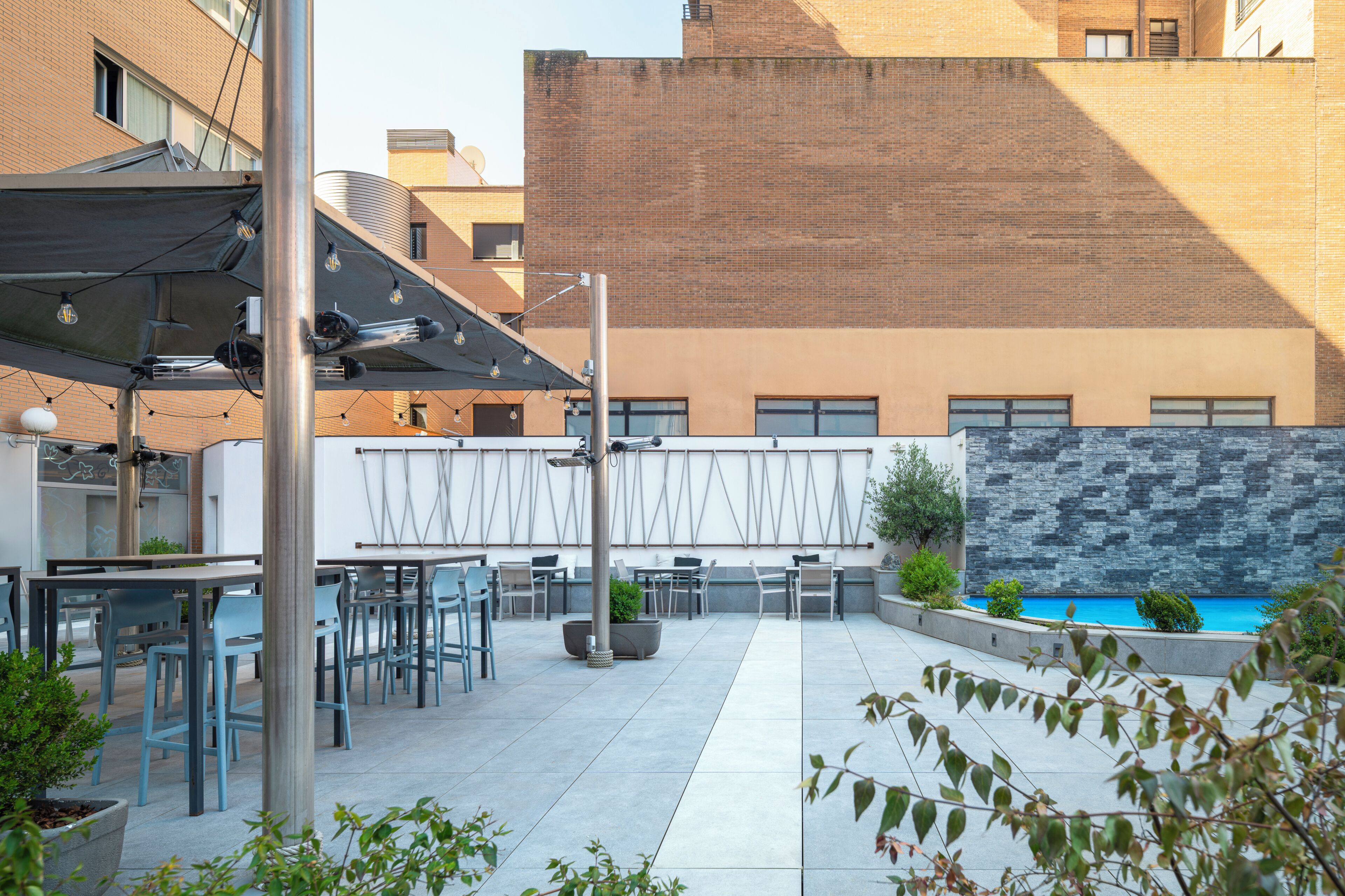 An outdoor patio area with tables and chairs, a pool, and a brick wall.